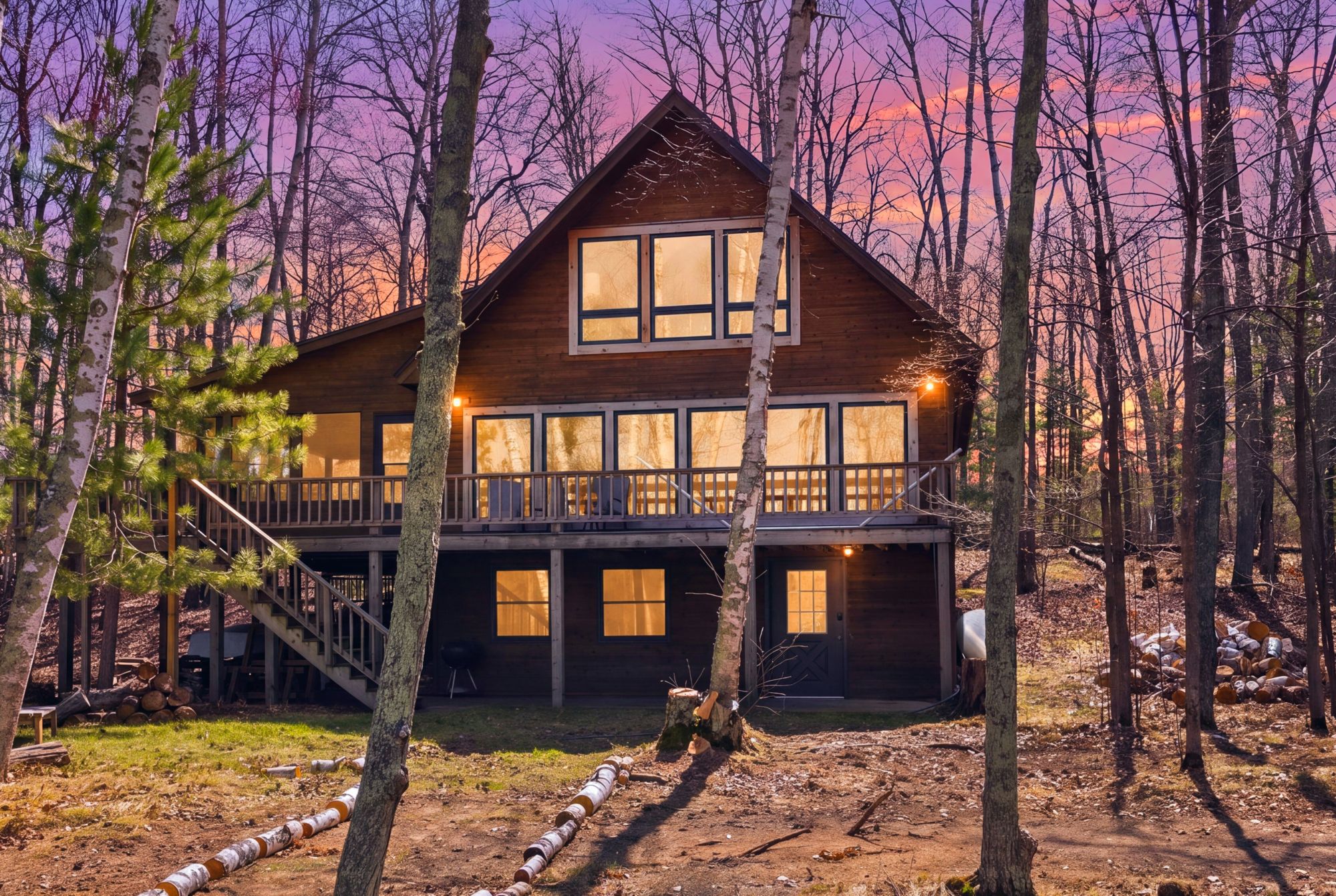 A-frame lake cabin at twilight with lights on